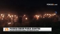 Santri Pondok Pesantren Raudhatul Amin berjalan membawa obor sambil melantunkan salawat saat pawai sambut tahun baru islam.